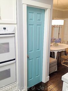 an open door leading to a kitchen with white cabinets and blue doors in the center