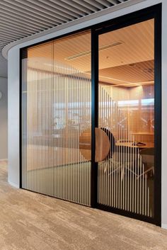 an office with sliding glass doors leading to the meeting room and desks in it