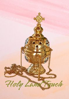 an ornate gold urn with a cross on the top and chain attached to it