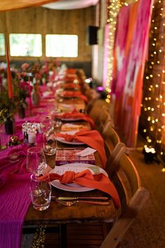 a long table is set with place settings and pink linens on the runneres