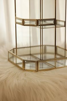 a three tiered glass display case on a fur rug