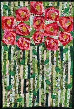 a quilted wall hanging with pink flowers on green and white striped strips in the background