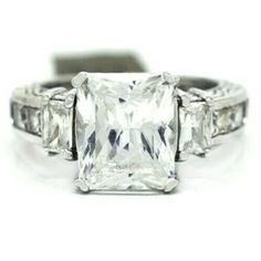 an engagement ring with a princess cut diamond in the center and three baguetts on each side