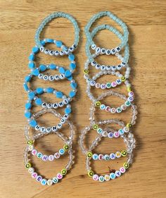 several bracelets that are sitting on top of a wooden table with beads and letters