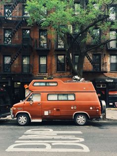 an orange van parked in front of a tall brick building with stairs on the side