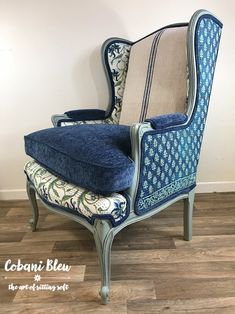 an old chair with blue upholstered fabric