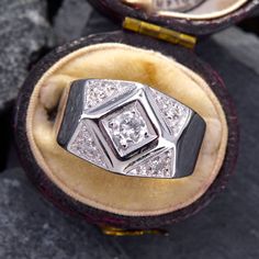 a diamond ring sitting in an open box on top of some rocks with the lid down