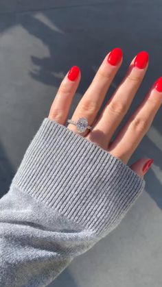 a woman's hand with red manicures and a ring on her finger