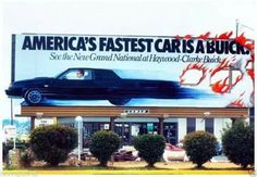 an advertisement on the side of a building for cars in front of a car dealership