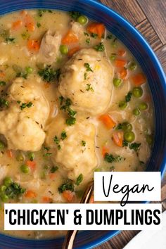 a blue bowl filled with chicken and dumplings next to a spoon on top of a wooden table