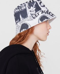 a woman with red hair wearing a black and white bucket hat that has images on it