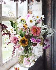 a vase filled with lots of different colored flowers on top of a window sill