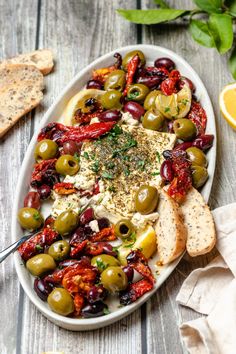 a platter filled with olives, cheese and crackers on a wooden table