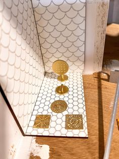 the inside of a white and gold bathroom with decorative tile on the floor, shower stall door