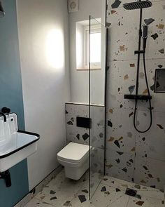 a white toilet sitting next to a bathroom sink under a shower head mounted faucet