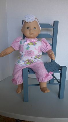 a baby doll sitting on top of a blue chair next to a white and gray wall