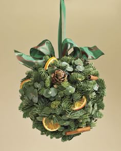 a christmas ornament with pine cones, oranges and greenery on it