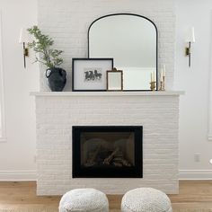 a white brick fireplace with two stools in front of it and a mirror above the fire place