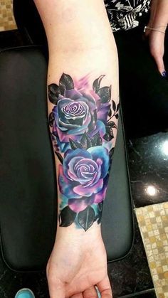 a woman's arm with flowers on it and her hand holding the wrist tattoo