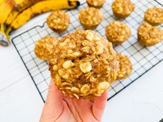 a person holding up a muffin in front of some bananas