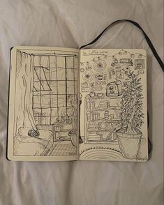 an open notebook with some drawings on it and a tree in the corner, sitting on a bed