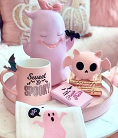 a table topped with pink items and a cup filled with coffee next to a small figurine