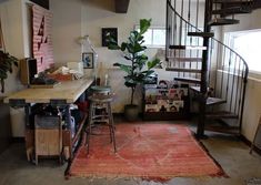 a living room with stairs and a rug on the floor in front of a table