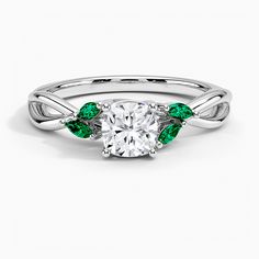 a white gold ring with green leaves on the band and a round cut diamond in the center