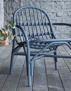 a blue chair sitting on top of a wooden floor next to a brick wall and potted plant