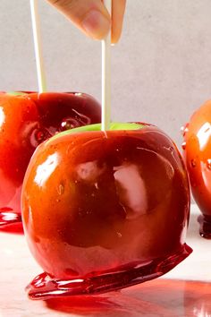 someone is picking up an apple with toothpicks from the top and dripping red liquid on the bottom