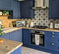 a kitchen with blue cabinets and wooden counter tops is pictured in this image, there is a potted plant next to the stove