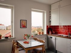 a kitchen with red tiles and white cabinets