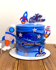 a birthday cake with blue frosting and stars on the top is sitting on a wooden table