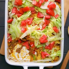 a casserole dish with lettuce, tomatoes and other vegetables in it