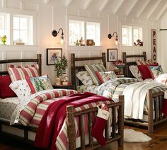 two beds in a room with white walls and wooden floors, one has a red blanket on it