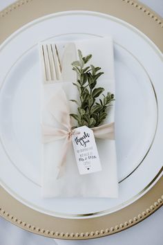 a place setting with napkins, silverware and greenery tied to the side