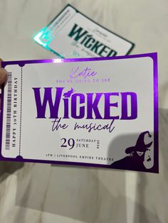 someone holding up a ticket for the musical's show, wicked the musical