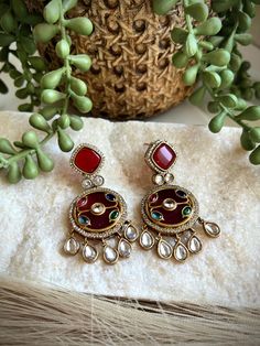 These exquisite earrings are handcrafted with intricate inlay work, featuring vibrant semi-precious stones set in a rich, red background. The intricate design is adorned with glistening crystals and accented with delicate crystal drops, creating a stunning and eye-catching pair of earrings. Crafted with meticulous attention to detail, these earrings are a true work of art. The inlay technique showcases the skill and artistry of the craftsperson, resulting in a unique and timeless piece of jewelry. Whether for a special occasion or as an everyday accessory, these earrings are sure to elevate any outfit and add a touch of elegance. Perfect for those who appreciate exquisite craftsmanship and one-of-a-kind designs. ------------------------------------------------------------------------------ Multicolor Jewelry With Matching Round Earrings, Elegant Multicolor Danglers With Intricate Design, Unique Metal Earrings For Festive Occasions, Fusion Style Jeweled Danglers For Diwali, Fusion Jeweled Danglers For Diwali, Unique Festive Metal Earrings, Fusion Style Intricate Dangle Chandelier Earrings, Red Kundan Dangle Jewelry, Traditional Multicolor Metal Earrings