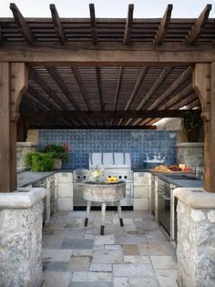 an outdoor kitchen with stone counters and grill