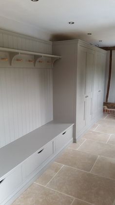 an empty room with white cabinets and shelves on the wall, in front of a fireplace