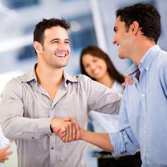 two men shaking hands with three women in the background