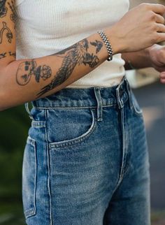 a woman with tattoos on her arm holding a cell phone