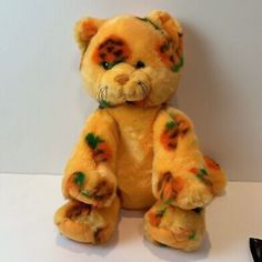 a yellow teddy bear with green leaves on it's chest and eyes sitting next to a pair of glasses