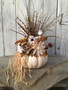 a white pumpkin filled with lots of flowers on top of a burlap table