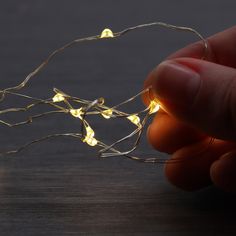 a hand holding a string of lights on top of a table