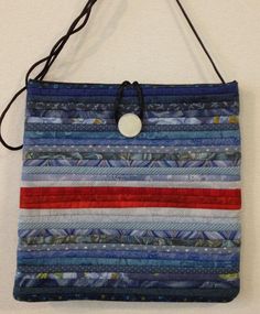 a bag made out of strips of fabric with a button on the front and side