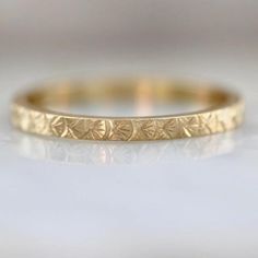 a yellow gold wedding band that has been engraved with leaves on the inside of it