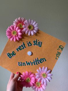 someone is holding up a graduation cap with flowers on it that says, the rest is still unwritten