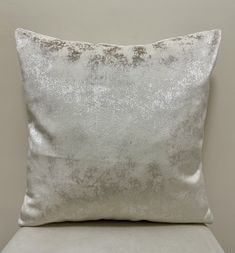 a silver pillow sitting on top of a white chair