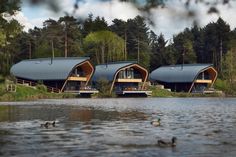 two large wooden buildings sitting on top of a lake next to tall grass and trees